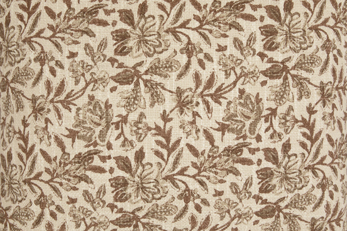 Close-up of tan fabric with brown botanical leaf and flower pattern texture.