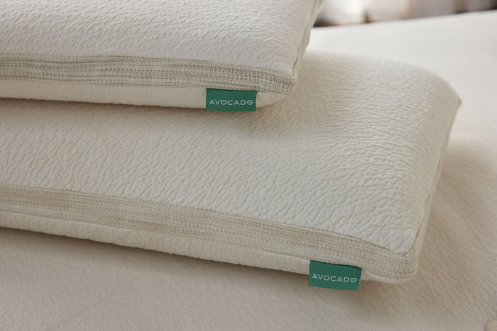 White latex pillow with green AVOCADO labels on seams, stacked close view