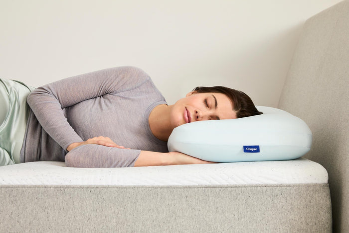Light blue Casper hybrid snow pillow with sleeper resting on a bed