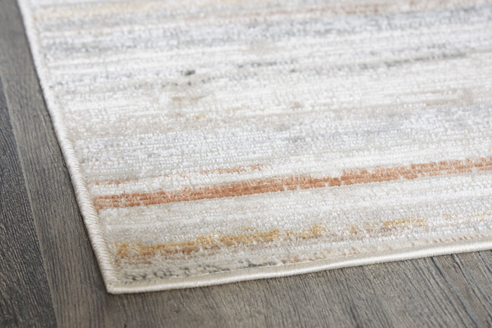 Corner closeup of light gray, cream, and tan striped rug with textured fibers