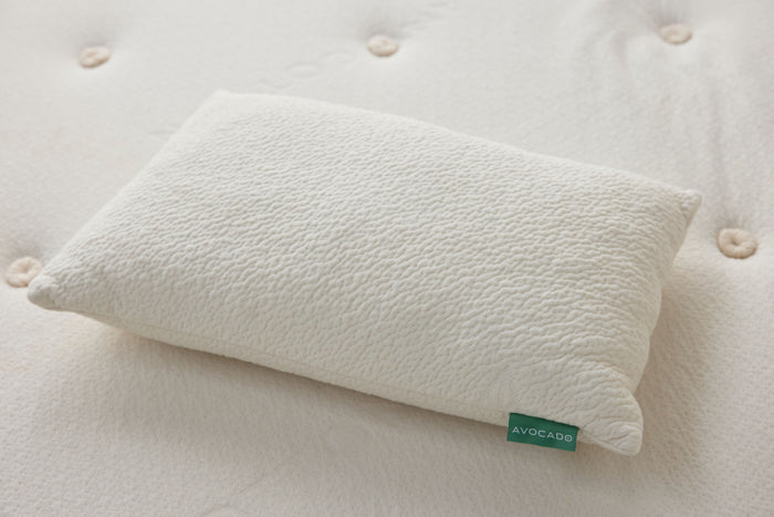Off-white throw pillow on tufted fabric with green label