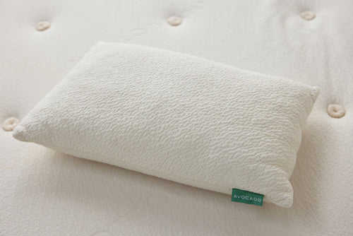 Off-white throw pillow on tufted fabric with green label