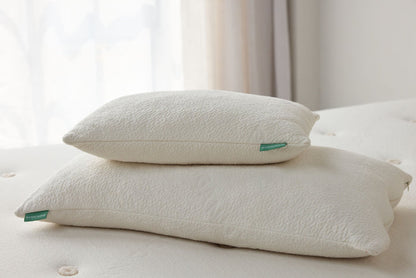 Two stacked off-white throw pillows with small green labels
