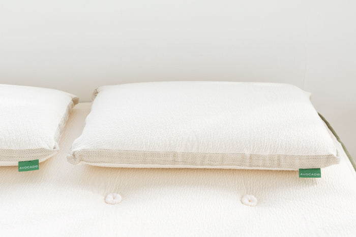White latex pillow pair with textured covers and green AVOCADO tags, top view