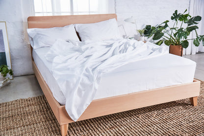 White organic cotton pillowcase on bed, neatly laid over the mattress
