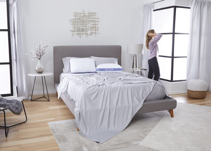 Performance pillow on a bed with white bedding in a bright bedroom