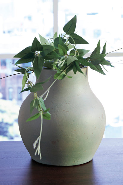 Light sage speckled ceramic vase with flared neck and curved belly, styled with green stems