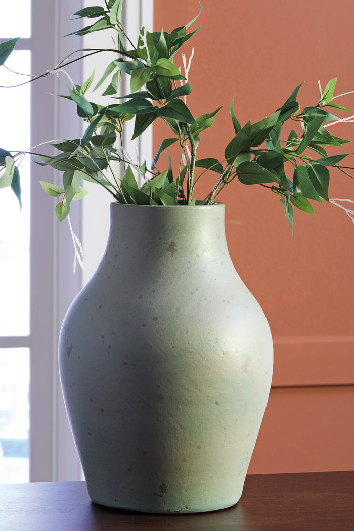 Light sage speckled ceramic vase with flared neck and tall rounded body, holding green stems
