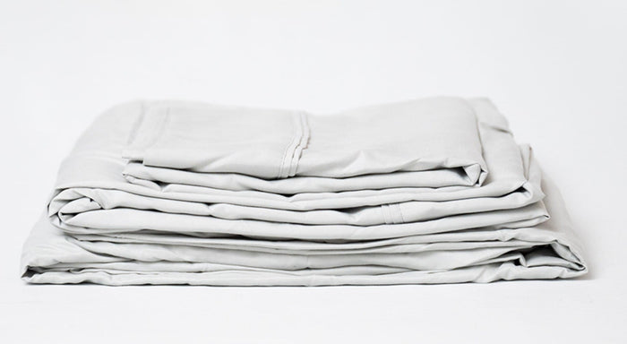 Light gray folded sheet set with stitched edges and layered corners