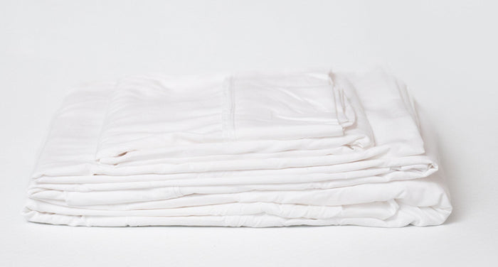 White sheet set in a folded, layered bundle with visible fabric folds