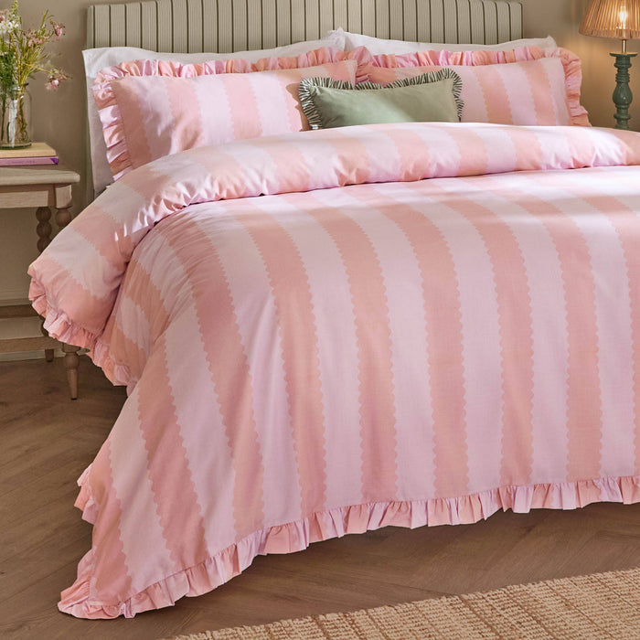 Pink striped bedding set on a bed in a bedroom setting.