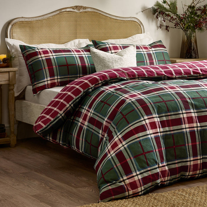 Bed with plaid bedding and wicker headboard in a bedroom setting