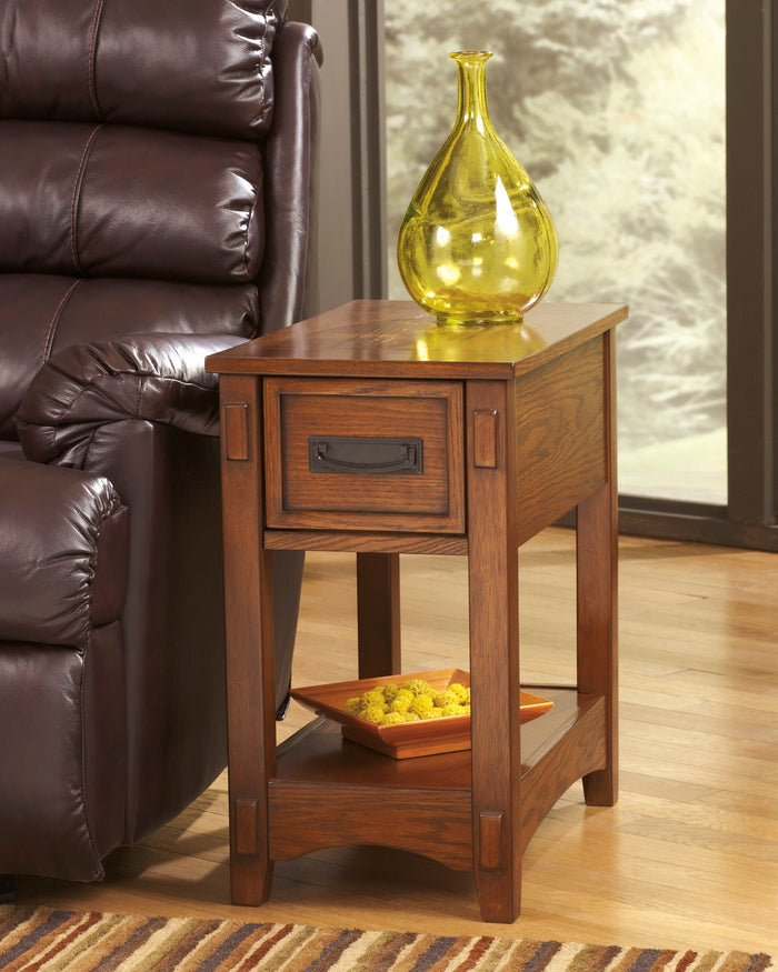 Cherry chairside end table with drawer and lower shelf, brass vase and lamp on top.