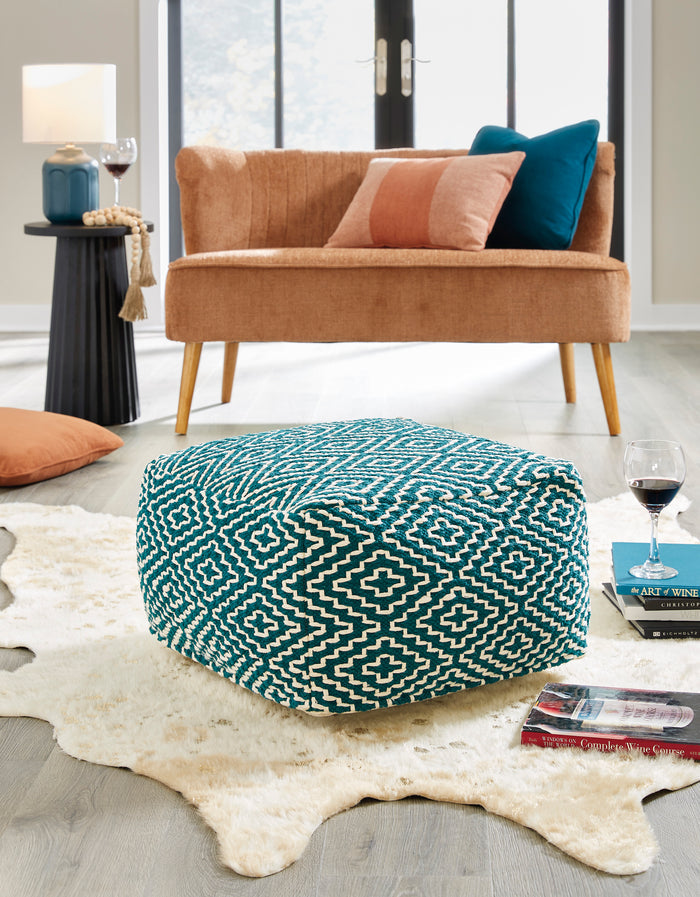 Teal geometric patterned pouf with diamond and cross motifs, rounded cube shape.