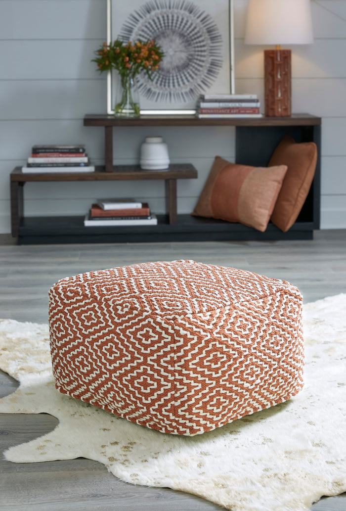 Orange geometric patterned pouf with repeating cross and diamond motifs, rounded cube.