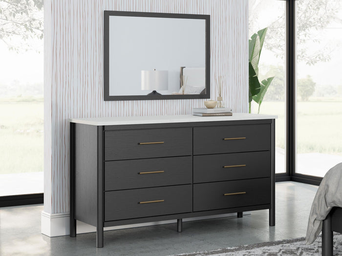 Square dark-framed mirror over black dresser with three double drawers and slim pulls