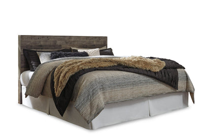 Dark wood panel headboard and white bed base with layered gray and tan bedding