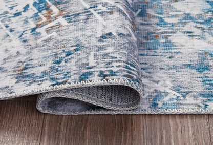 Blue-and-white abstract rug edge close-up with stitched border and backing.