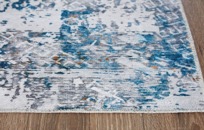Blue-and-white abstract rug surface with distressed motifs near corner edge.