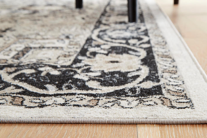 Close-up of geometric area rug corner with black motifs on light gray ground
