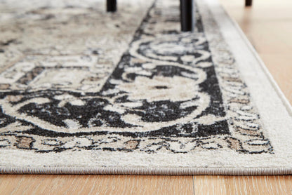 Close-up of geometric area rug corner with black motifs on light gray ground