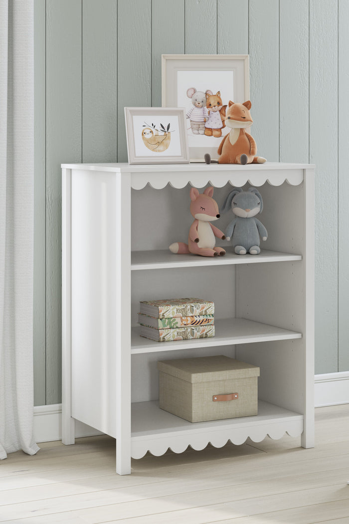 White bookcase with scalloped trim, three open shelves, and a bottom drawer