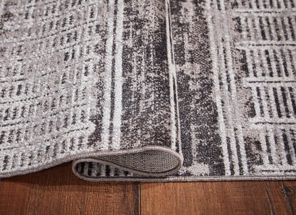 Gray and white striped area rug close-up, rolled edge showing textured pile