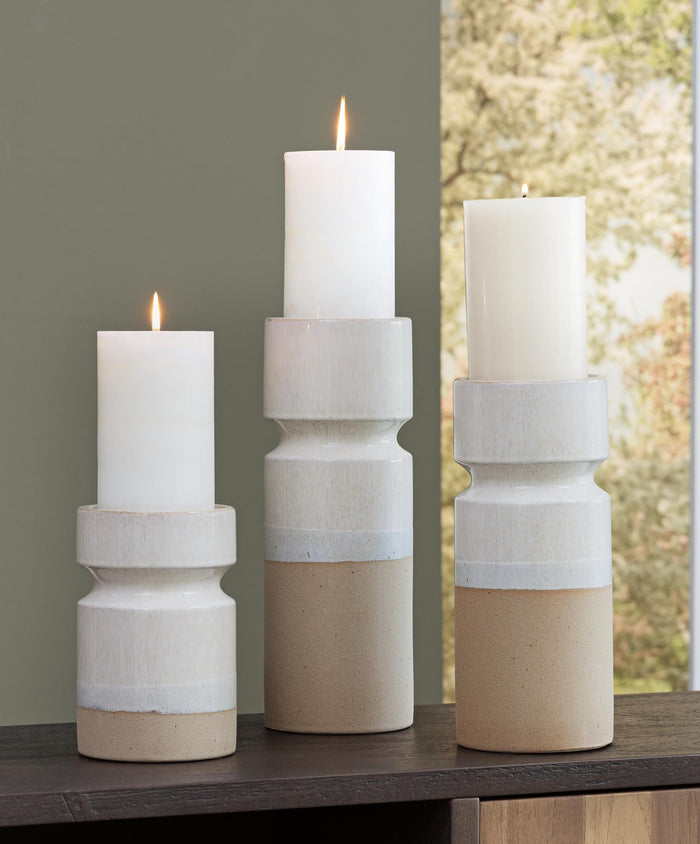 Three ceramic candle holders holding white pillar candles with blue middle stripe