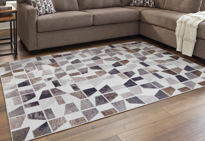 Geometric area rug on floor, gray and brown blocks with white and dark accents
