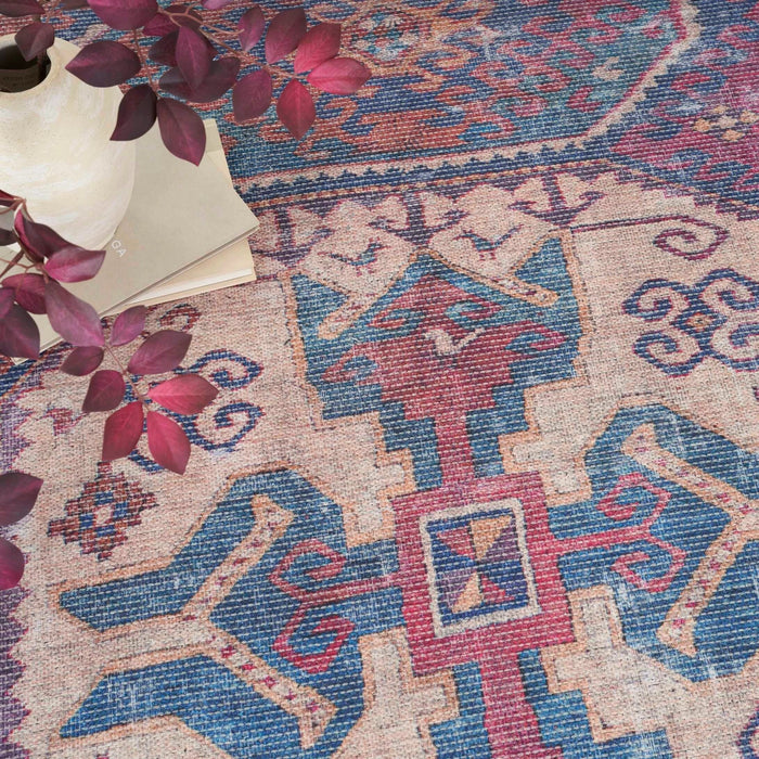 Close-up of washable rug with cream background, red accents, and blue geometric shapes.