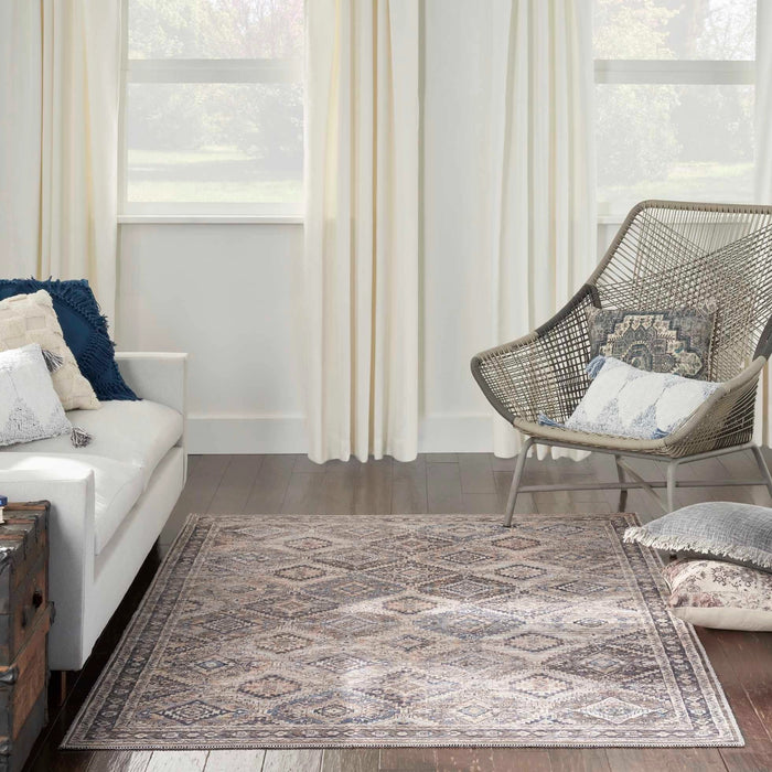 Geometric patterned area rug in beige and blue, rectangular border on dark floor