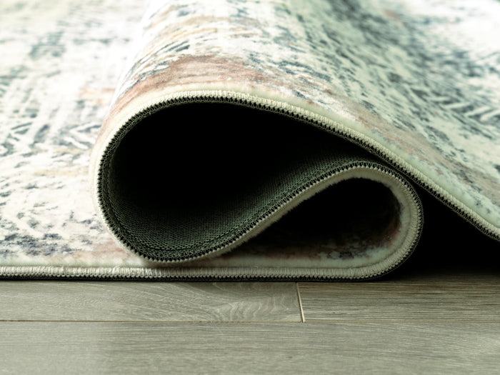 5x7 area rug edge close-up with stitched border and teal-gray abstract pile