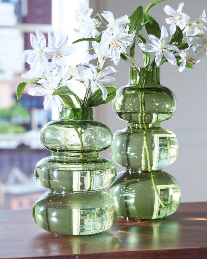Set of green glass vases with stacked rounded shapes, each holding white flowers