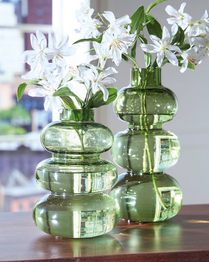 Set of green glass vases with stacked rounded shapes, each holding white flowers