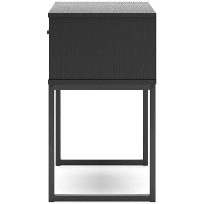 Dark wood nightstand with one drawer and metal bar pull, back view on four legs.