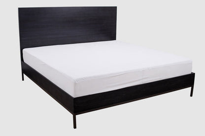 Queen bed with white fitted mattress protector cover on top