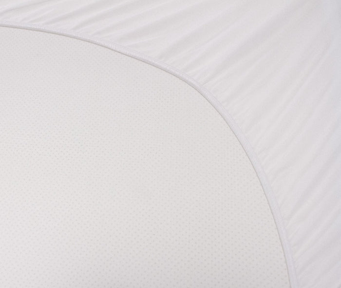 White mattress protector fabric close-up with textured dotted surface and curved edge