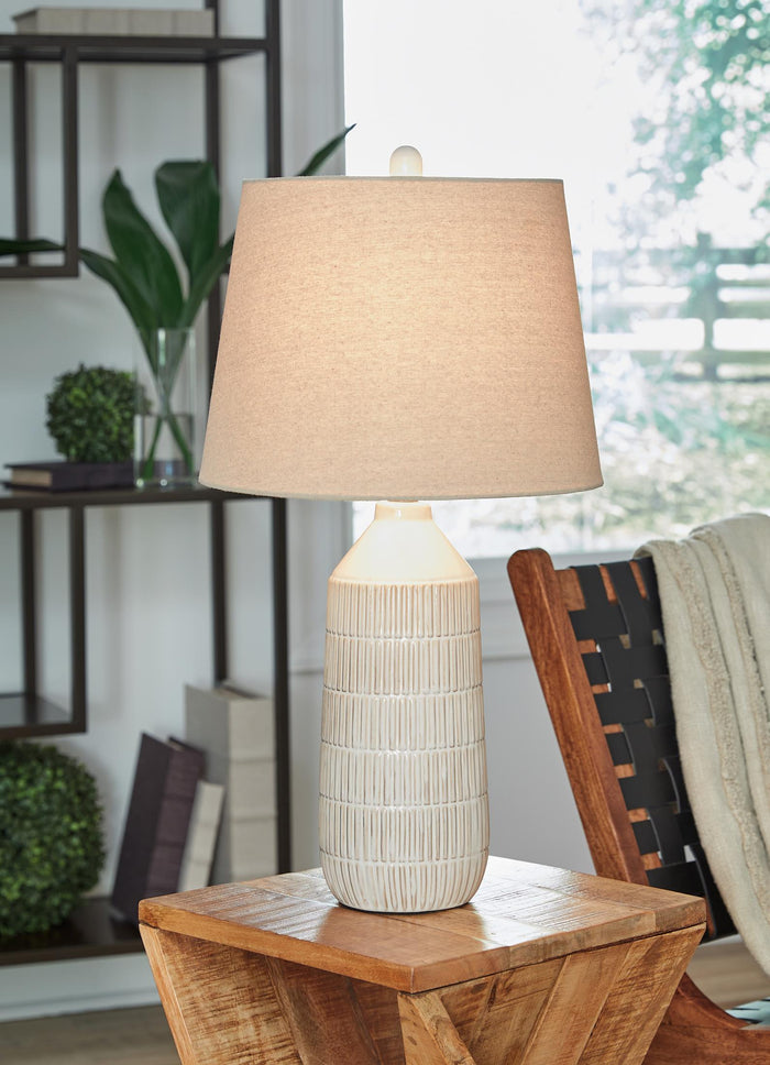 Table lamp with beige fabric shade and ribbed ceramic base on a side table