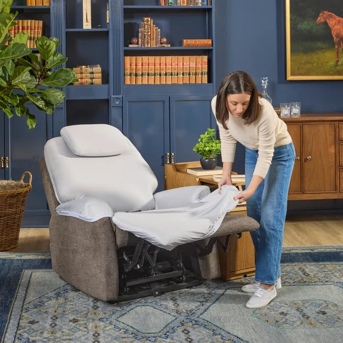 Light gray recliner chair with extended footrest, shown with white sheets being fitted.